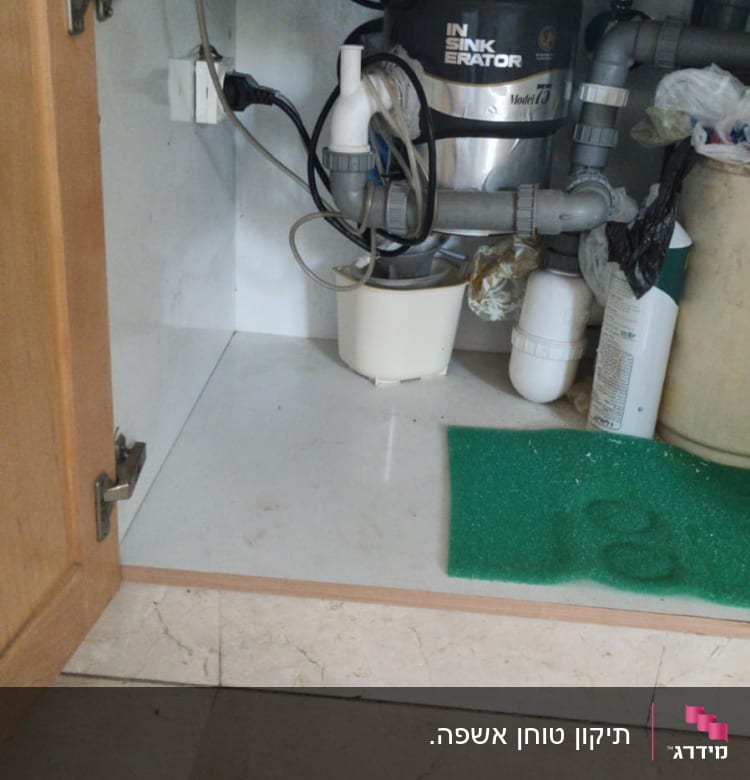 כיור עם מערכת סינון מים וצנרת מתחת לארון